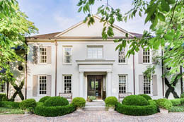 красивый белый оштукатуренный симметричный фасад колониального двухэтажного дома