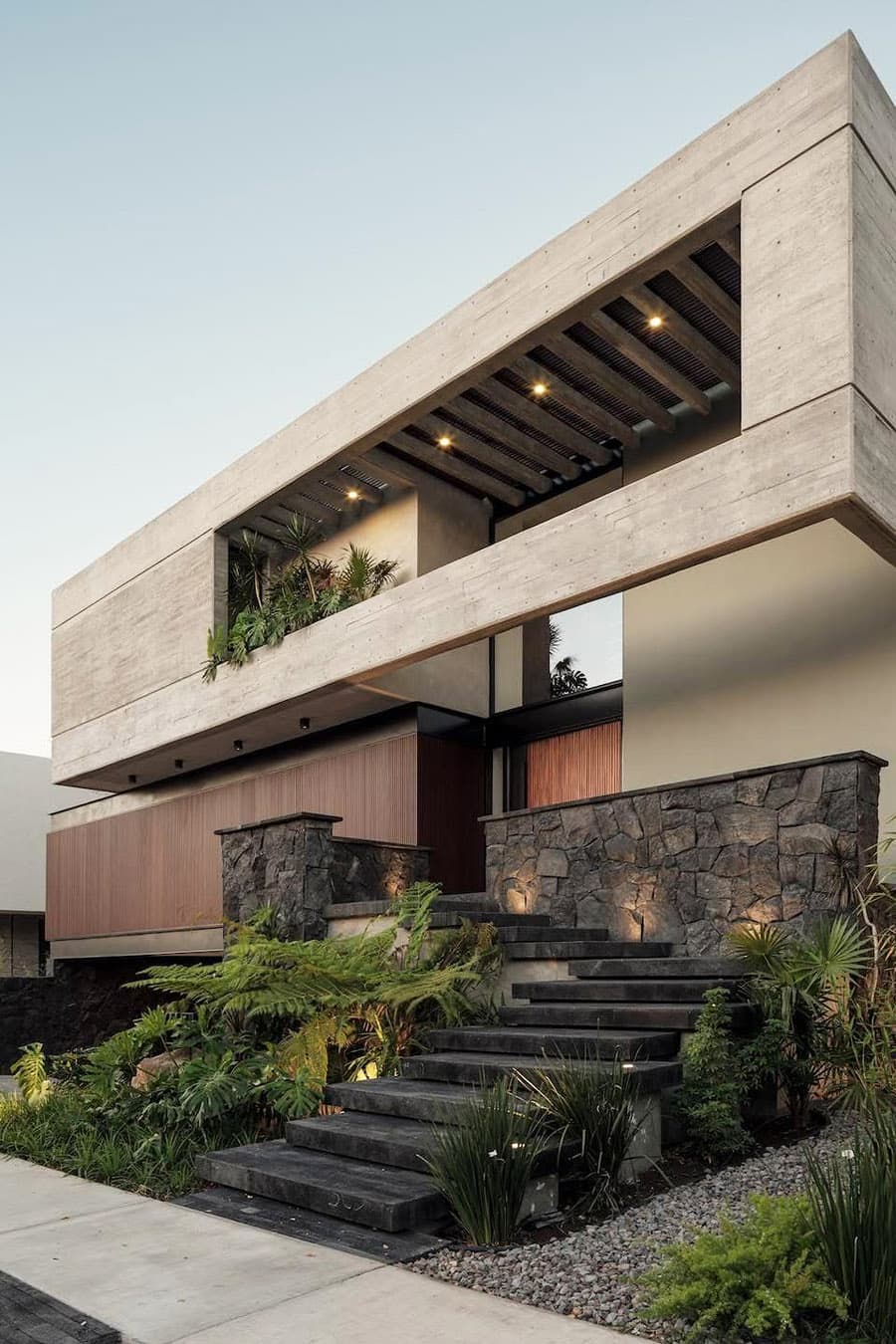 дизайн фасада пластичного решения современного дома с графитовой лестницей в натуральном камне, интересной входной группой и отделкой второго этажа в бетоне, гравийная отмостка - Di Frenna Arquitectos, Mexico