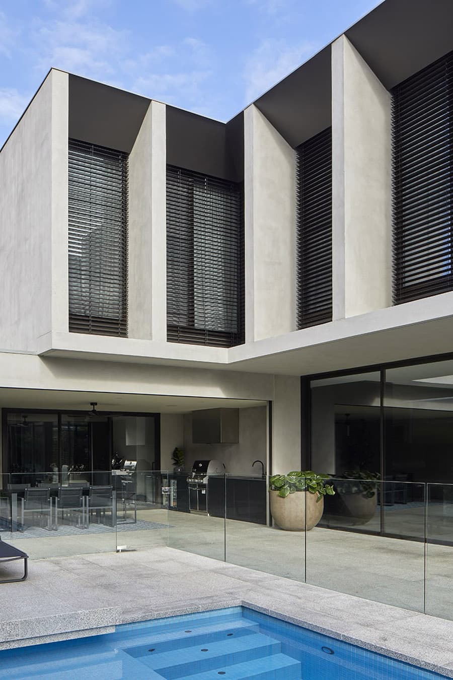 фрагмент фасада современного частного дома в штукатурке с алюминивыми ламелями жалюзи на окнах, скошенные верхние откосы оконных проемов - KILRUSH House