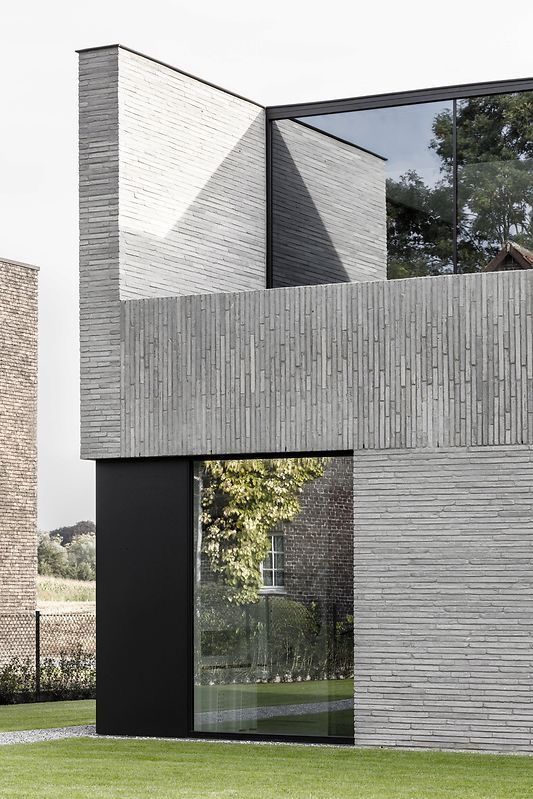 фото современной отделки фасада узкой клинкерной плиткой в двух направлениях с штукатурными акцентами цвета темный графит