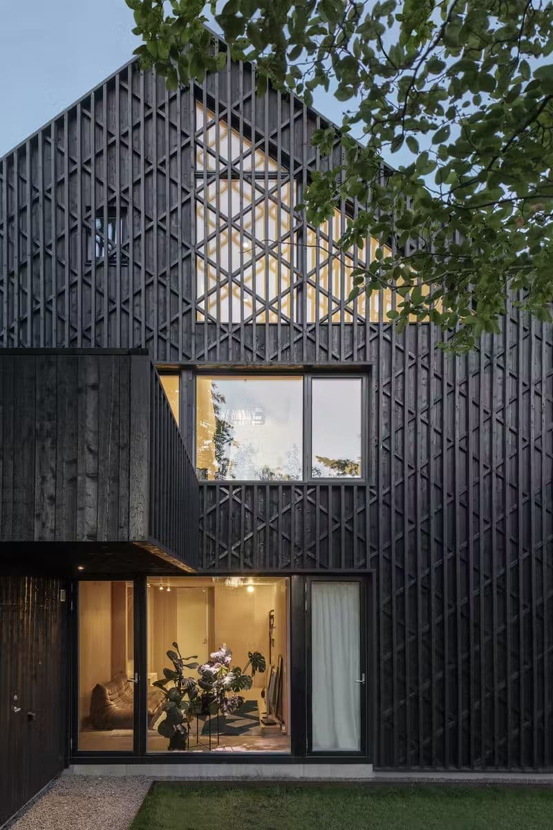 монохромный черный фасад современного шведского дома с использованием ромбовидных ажурных реек и обожженных досок