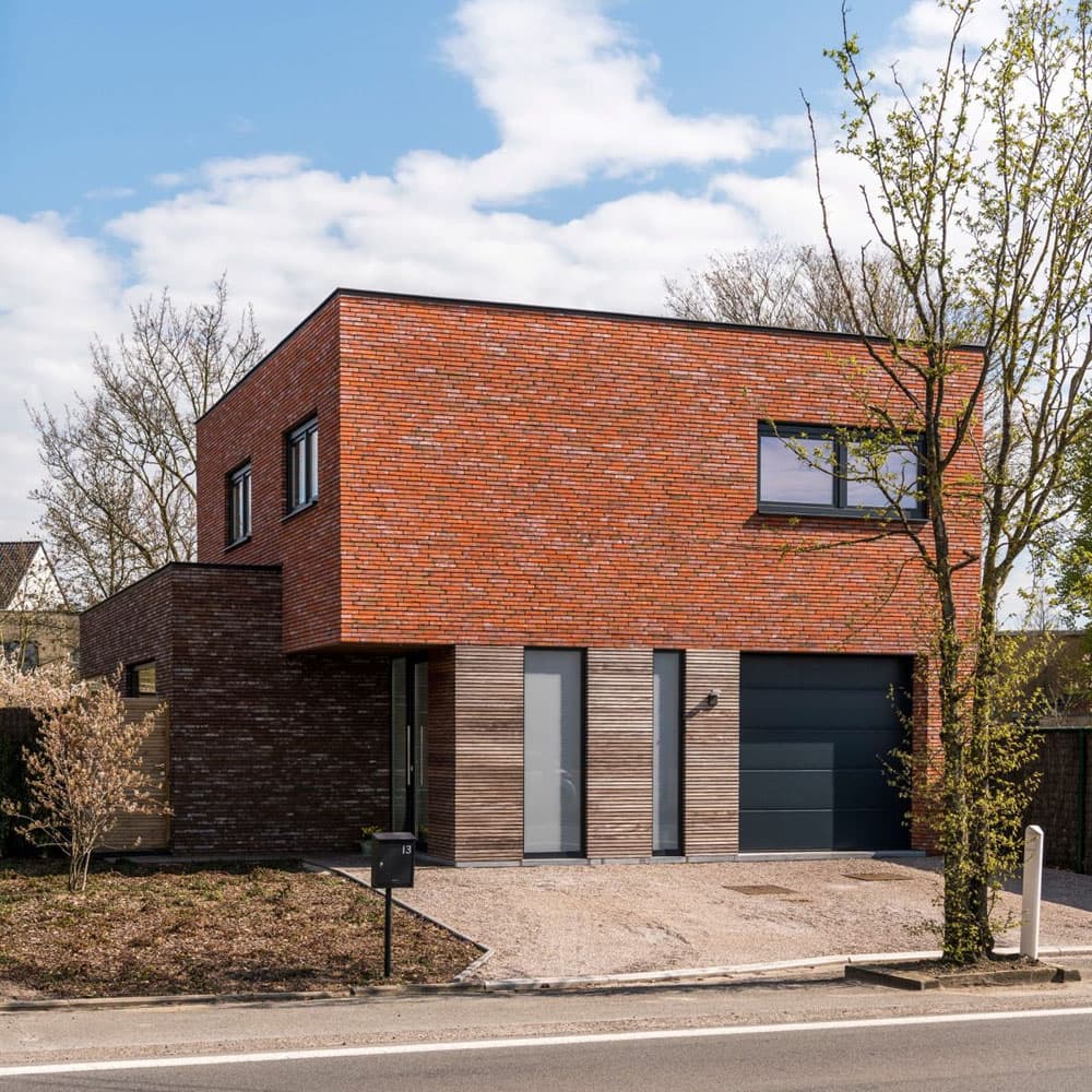 Небольшой жилой дом с кирпичной отделкой фасадов и небольшими окнами