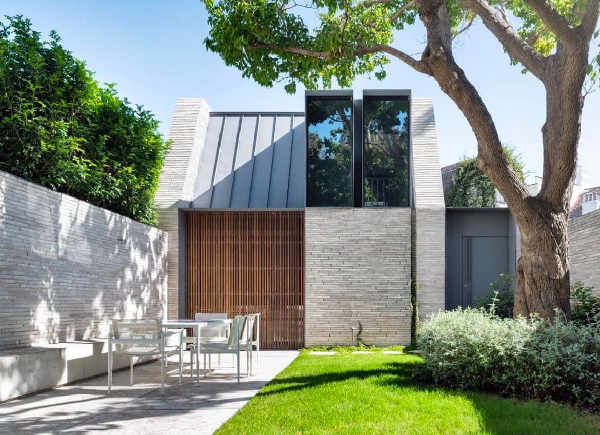 Небольшой жилой дом с кирпичной отделкой фасадов и необычными окнами