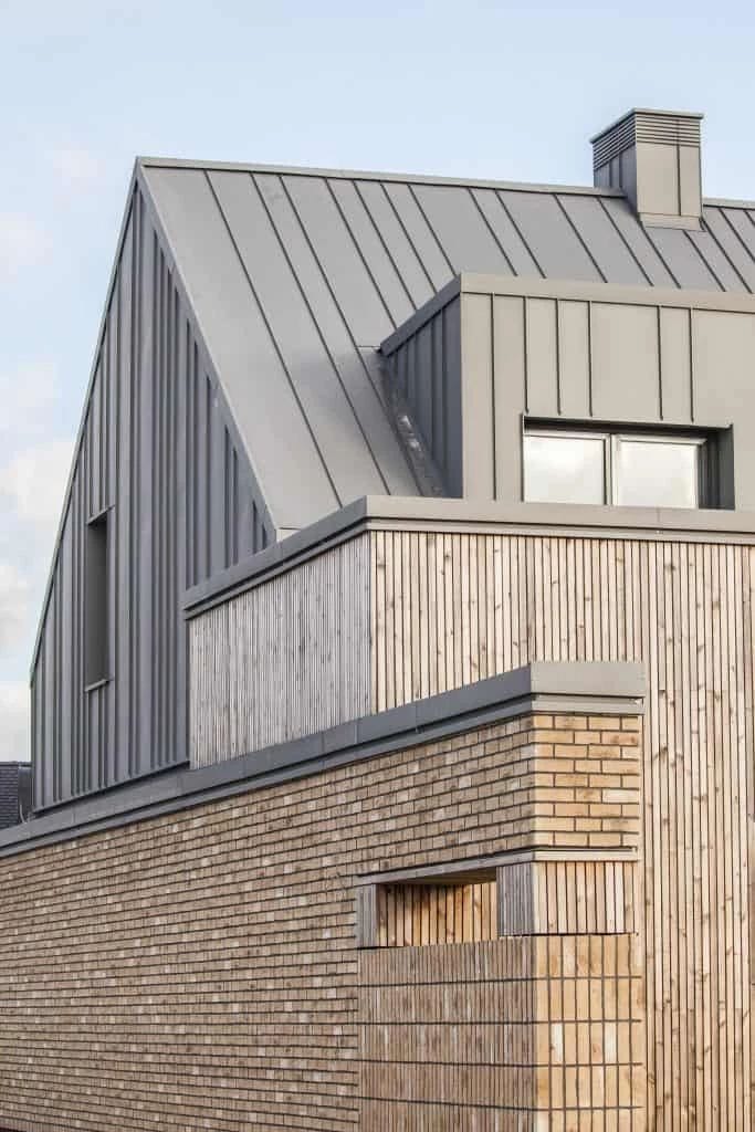 металлическая отделка серым фальцем, соломенный кирпич и вертикальные рейки подчеркивают современные архитектурные формы данного здания