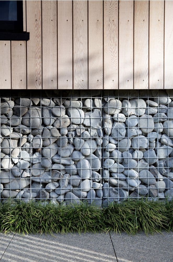 фрагмент фото современного фасада - габионы на цоколе, деревянная вертикальная доска на стенах, ничего лишнего - в дизайне так тоже можно