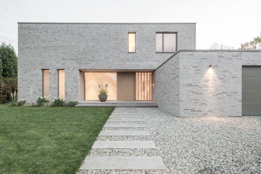 в дизайне этого современного двухэтажного дома архитектор использовал моноотделку из белого пестрого клинкера с мягкими оттенками серого оконных рам и ворот