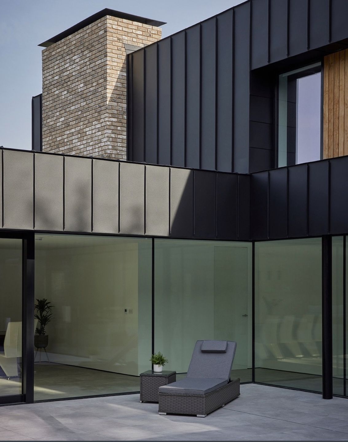 часто в современном дизайне фасадов используют такое сочетание материалов - графитовый фальц, планкен из натурального дерева теплых оттенков, клинкерный кирпич или плитка