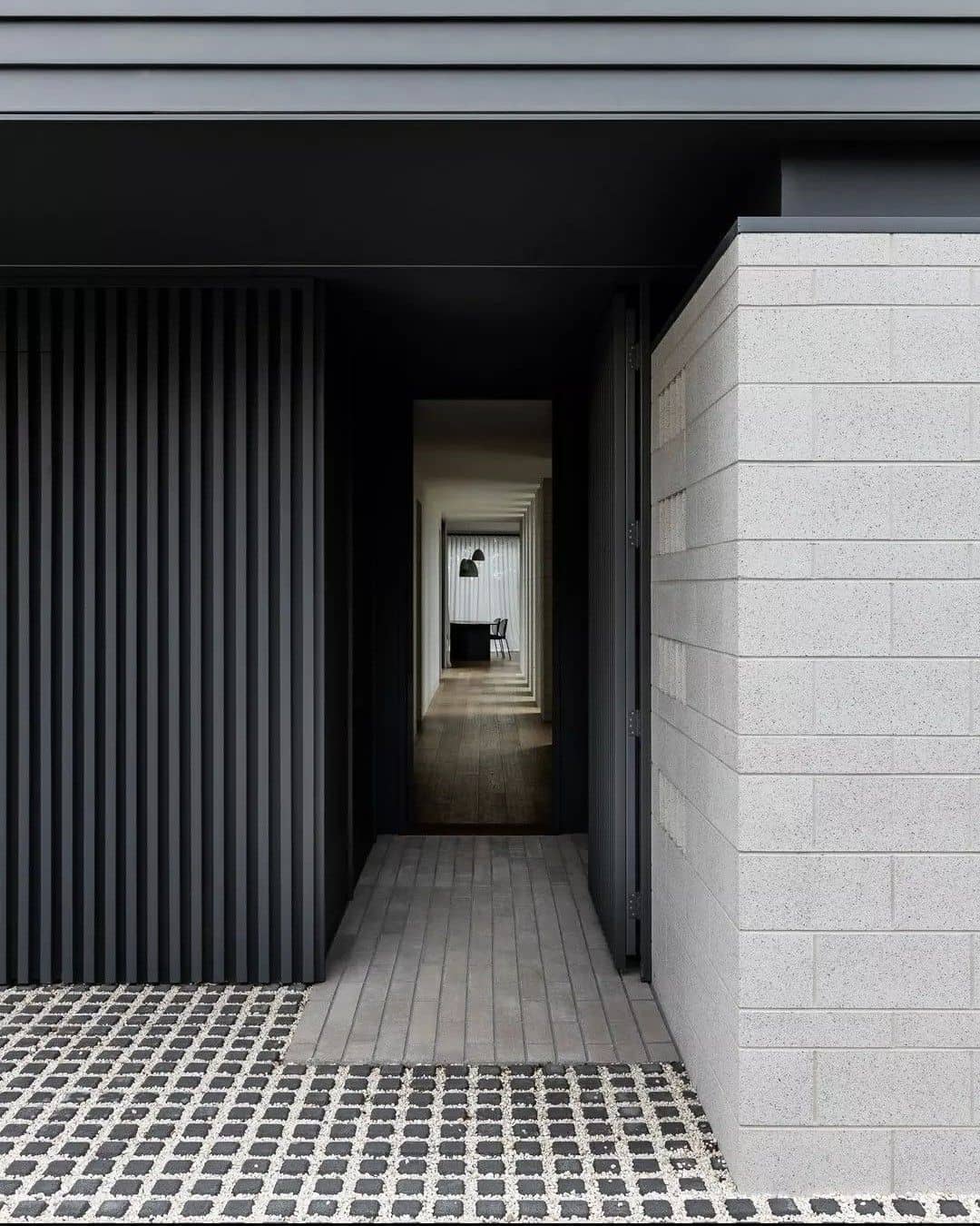 входная группа дома в современном стиле - панели под рейку графитового цвета, фасадная плитка из камня, мозаичный пол из сланца и мелкой гальки