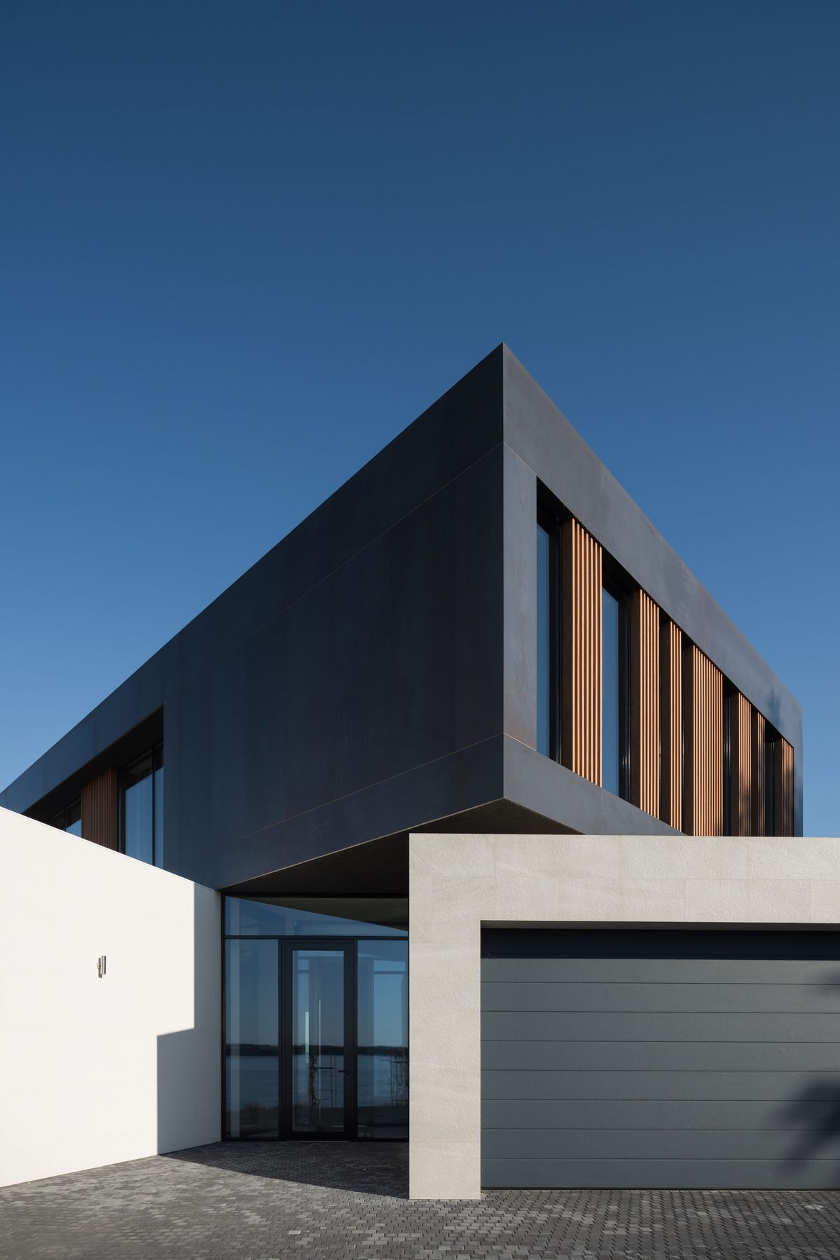 керамогранитный фасад второго этажа дома в современном стиле с дополнительной отделкой плиткой из изветняка и декоративной штукатуркой в уровне первого этажа