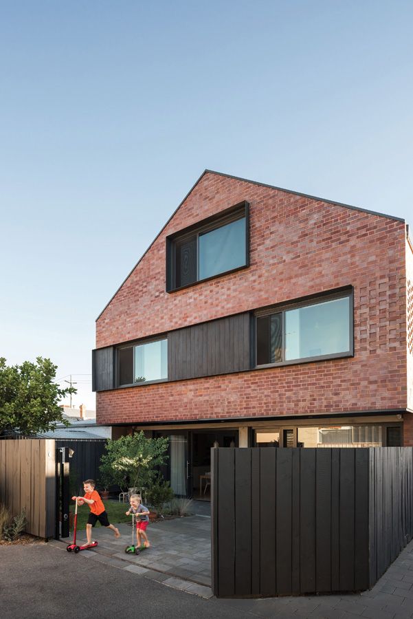 кирпичный фасад двухэтажного дома с мансардой в современном стиле - большие окна и контрастная деревянная отделка с откосами из металла графитового цвета