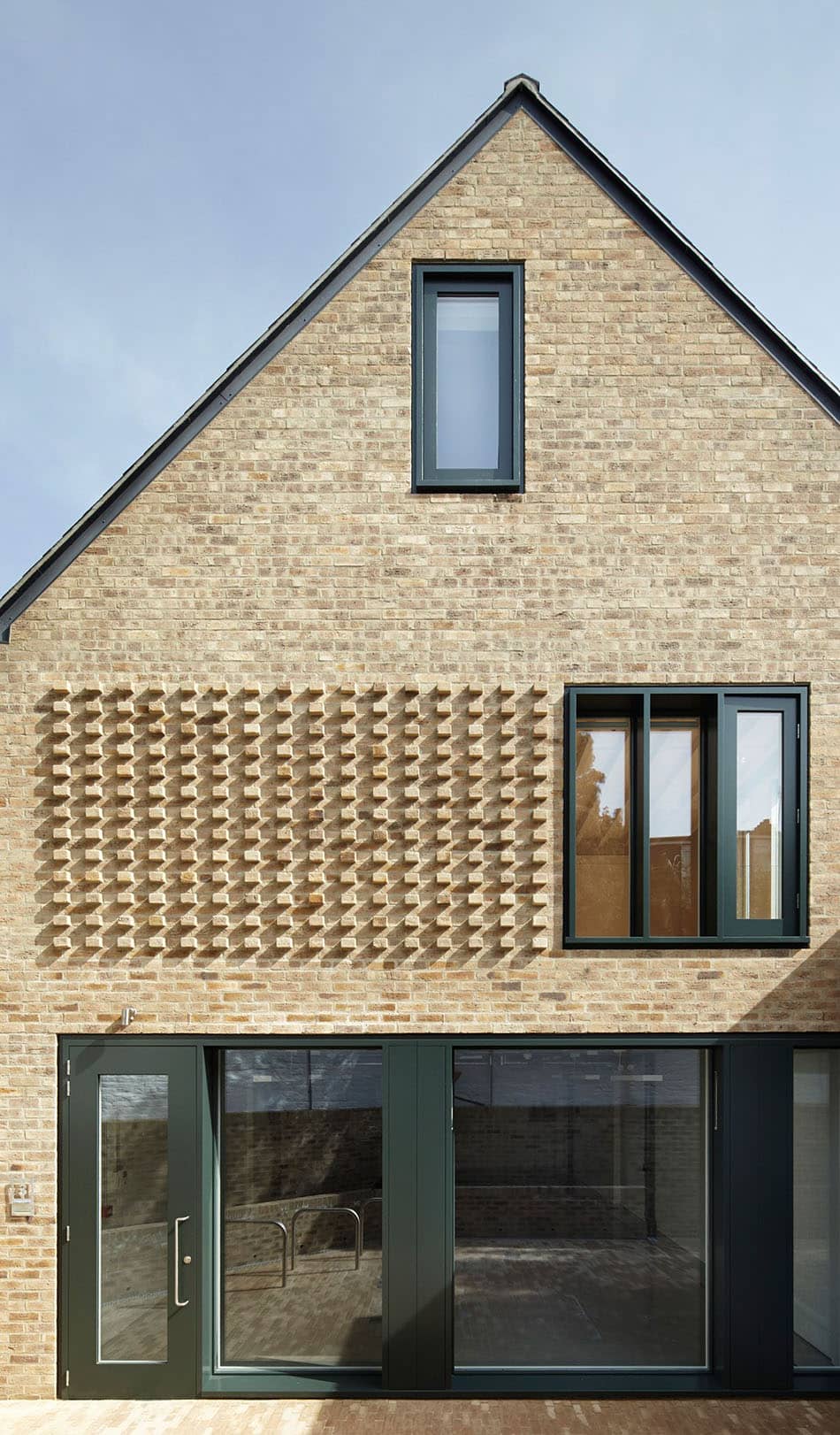 проект фасада современного кирпичного дома с использованием элементов объемной кладки - темно-зеленые двери и рамы окон отлично гармонируют с песочным цветом кирпича