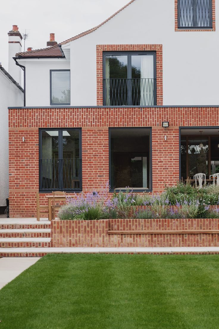 современный классический стиль этого небольшого дома хорошо иллюстрирует как минимальными средствами можно создать эффектный фасад - яркая клинкерная плитка, серые рамы окон и белая декоративная штукатурка