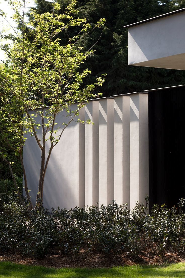 интересный пример современного ограждения участка - глухая штукатурная стена переходящая в пилоны с четким ритмом - хорошо подойдет к фасадам дома в минималистичном стиле