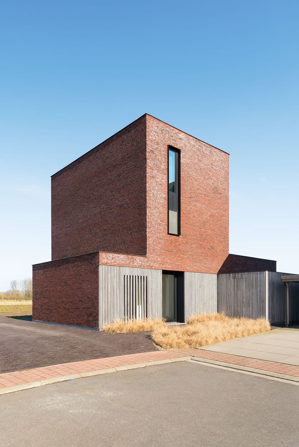 этот долговязый дом являет собой яркий пример современного архитектурного подхода в проектировании - простые гармоничные объемы и два типа отделки - клинкерная плитка и вертикальная рейка