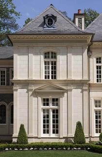 фасад классического каменного двухэтажного особняка с крышей из серой битумной черепицы и треугольным сандриком