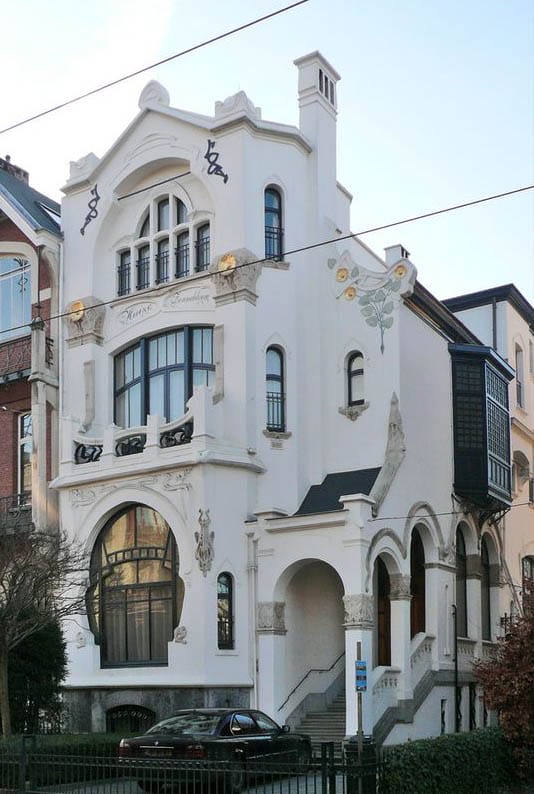 белый оштукатуренный фасад дома в стиле ар-нуво с боковой входной группой