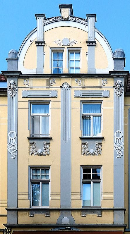 фото фрагмента штукатурного бежево-песочного фасада здания с серыми пилястрами в стиле европейского модерна