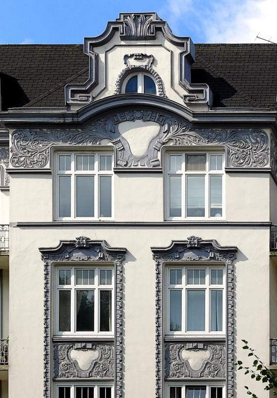 штукатурный фасад здания с красивым барельефом и обрамлениями серого цвета в стиле модерн