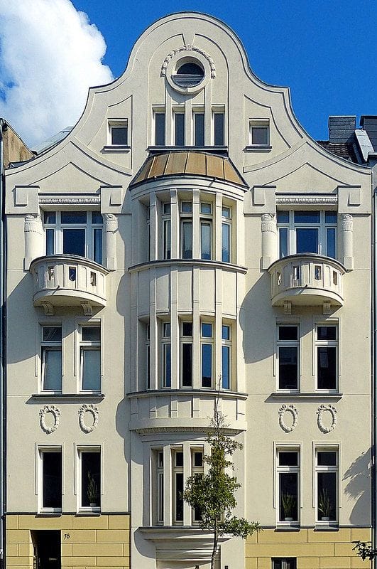 фото симметричного фасада эпохи ар-нуво - бежевая штукатурка с рустованным низом