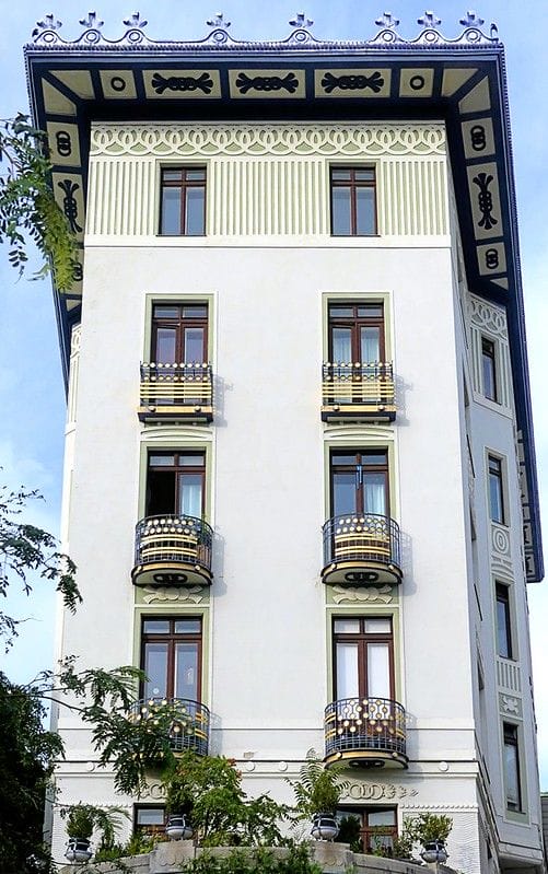 фото примера отделки здания в стиле модерн с использованием штукатурки светло-серого цвета и зеленых обрамлений