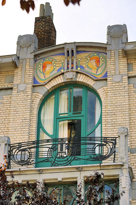 бежевый кирпичный фасад особняка с орнаментальной росписью над дверью балкона