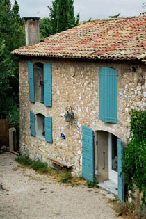 разноцветная черепица и бирюзовые ставни на фасаде каменного дома в стиле прованс