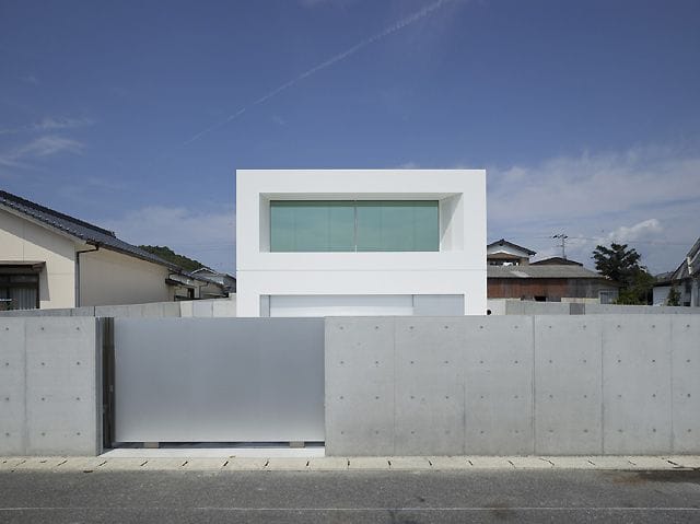 Серый бетон, разделенный на секции в гармонии с гладкой монолитной панелью ворот