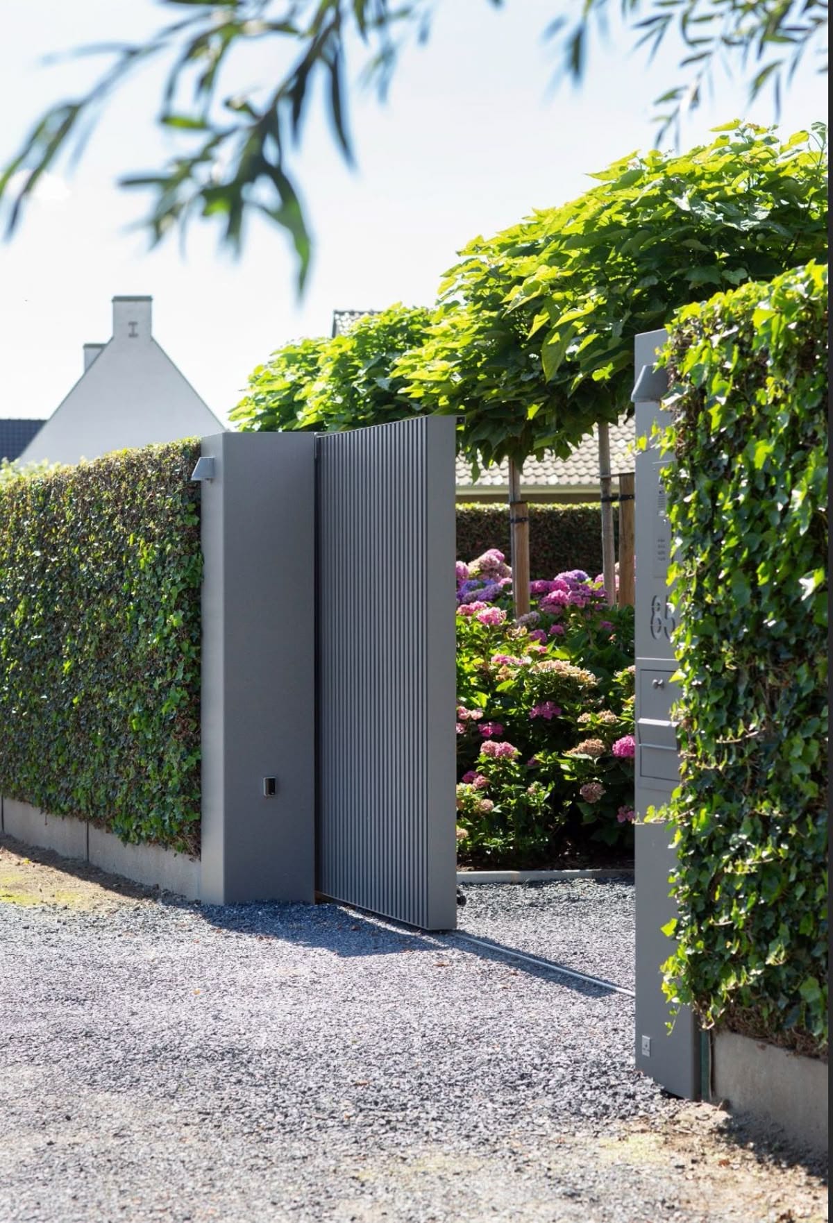 Стены из зелени на контрасте выдержанного серого цвета столбов и вертикальных алюминиевых реек